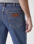 Achteraanzicht van een blauwe spijkerbroek met Wrangler logo op de achterzak.