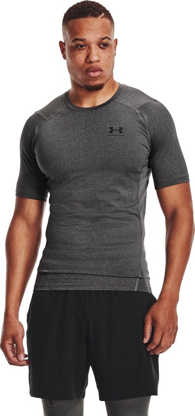 Man met donkergrijs, kort, nauwsluitend sportshirt met grijze panelen.