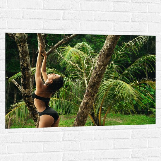 Muursticker - Vrouw Poserend bij Palmbomen in de Jungle - 105x70 cm Foto op Muursticker