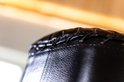 Close-up van de gestikte rand van een zwarte AJ-Sports bokspaal.