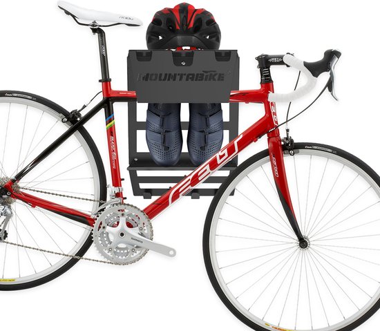 Een rode racefiets met een zwart ophangsysteem met zwarte schoenen en helm erop.