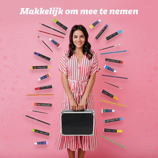 Vrolijke vrouw in gestreepte jurk met koffer, omringd door kunstbenodigdheden op roze achtergrond.
