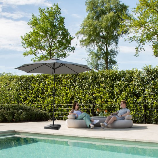 Grijze parasol, open, met een stel op loungebanken bij een zwembad.