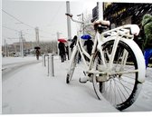 PVC Schuimplaat- Fiets Geparkeerd in Stad tijdens Sneeuwbui - 80x60 cm Foto op PVC Schuimplaat