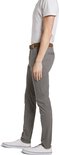 Man in grijze chino, bruine riem, wit T-shirt en witte sneakers.