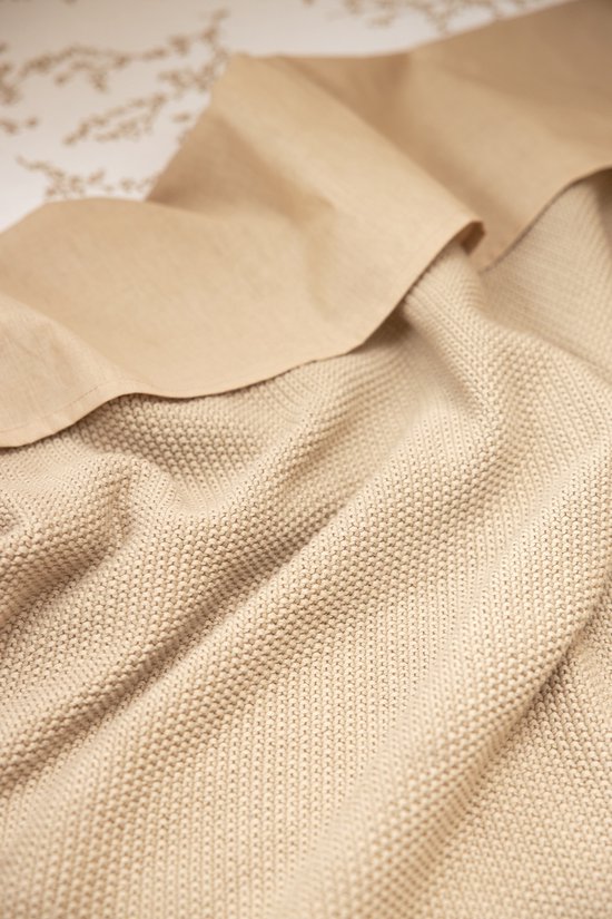 Een beige gebreide deken met textuur.