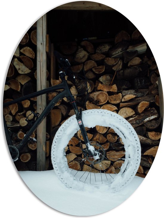 PVC Schuimplaat Ovaal - Zwarte Fiets Geparkeerd voor Houtstapel in de Sneeuw - 72x96 cm Foto op Ovaal (Met Ophangsysteem)