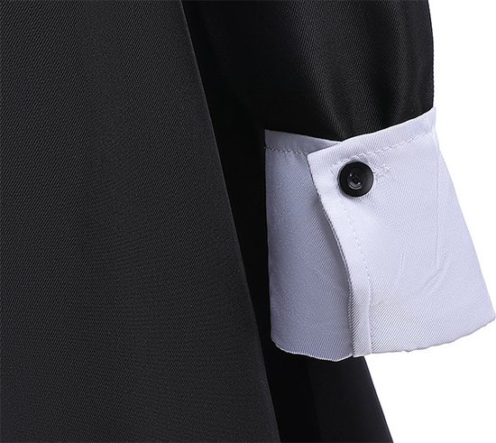 Détail de la robe noire avec un poignet blanc et un bouton noir.