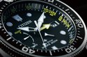 Close-up van de wijzerplaat van een zwart Citizen Promaster duikhorloge.