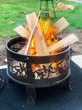 Zwarte Gardebruk vuurkorf met brandend hout, op een zwart kleed in de tuin.