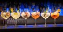 Zes gevulde cocktailglazen met diverse fruit garnituren en rietjes.