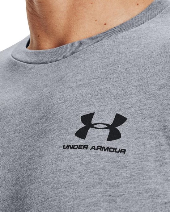 Detailopname van een grijs Under Armour t-shirt met zwart Under Armour logo en tekst op de linkerborst.