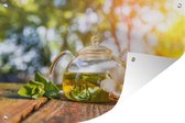 Tuinposter - Tuindoek - Tuinposters buiten - Een doorzichtige theepot met thee in het zonlicht - 120x80 cm - Tuin