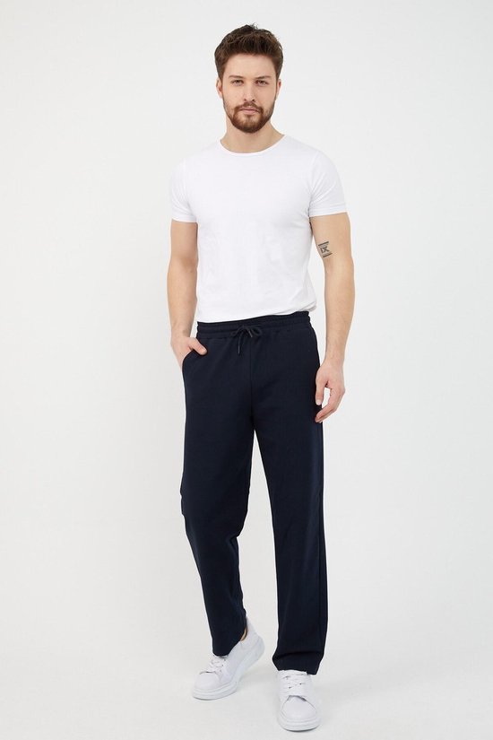 Man in witte T-shirt en navy joggingbroek met trekkoord en steekzakken.
