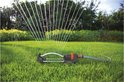 Zwenksproeier op gras met oranje connector, sproeit water in de verte.