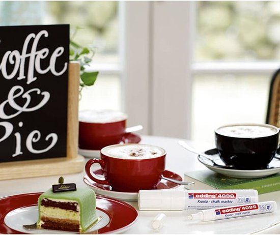 Taartje, koffies met schuim en twee witte edding krijtstiften op een tafel.