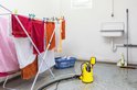 Gele dompelpomp met vlotterschakelaar naast een droogrek met rode, oranje en witte handdoeken.