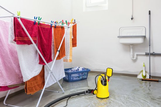 Gele dompelpomp met vlotterschakelaar naast een droogrek met rode, oranje en witte handdoeken.