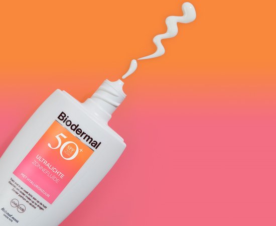Biodermal Ultralichte Zonnefluide SPF 50+ flesje met een witte crème die eruit spuit op een oranje/roze achtergrond.