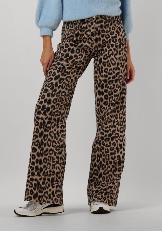 Model draagt een broek met luipaardprint, wijde pijpen, met een lichtblauwe trui en sneakers.