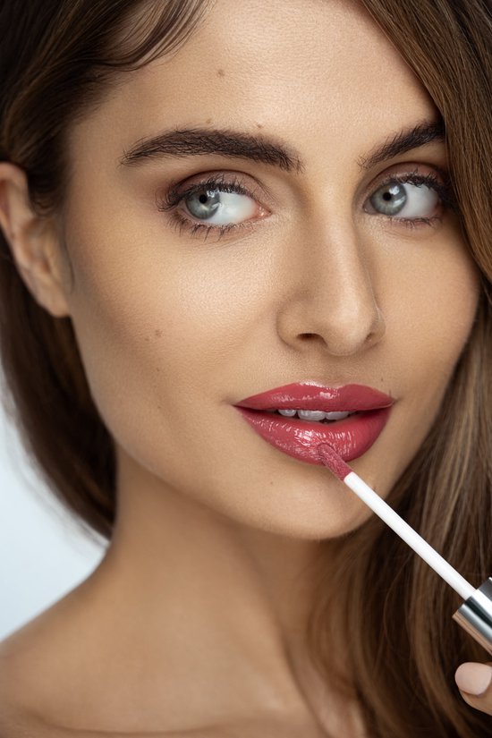 Model met glanzende, roze lippenstift die aangebracht wordt met een applicator.