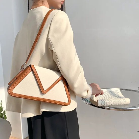 Crèmekleurige schoudertas met bruine accenten, gedragen door een model met beige blazer.