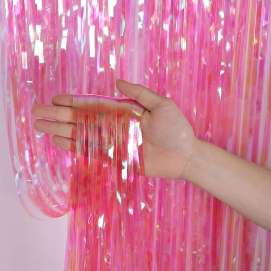 Hand houdt glinsterende, roze slierten van een feestgordijn vast.