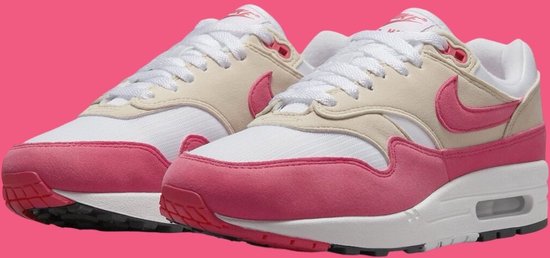 Close-up van witte Nike sneakers met roze en beige overlays, roze Swoosh en roze mudguard.