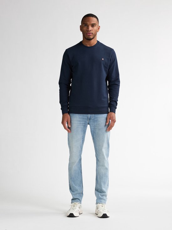 Man met donkerblauwe sweater en lichtblauwe jeans