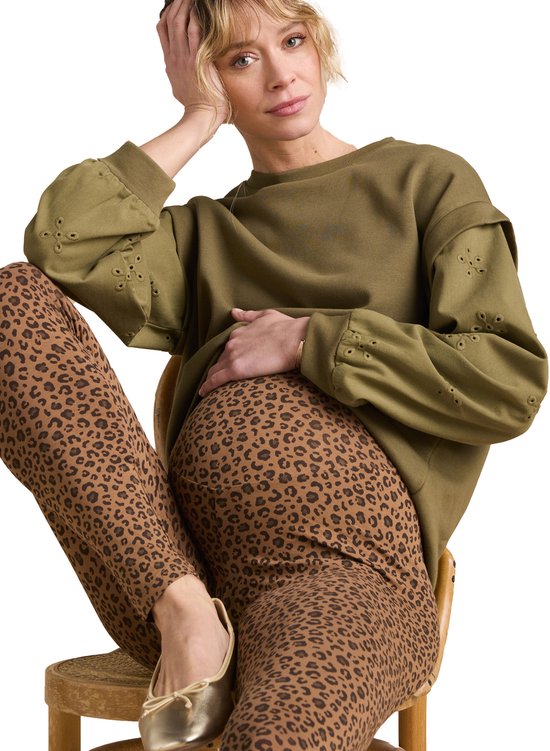 Zwanger model in bruine legging met luipaardprint en kaki trui met geborduurde details op de mouwen.