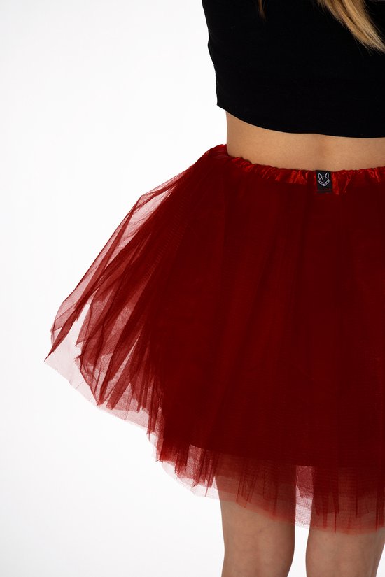 Detail van een donkerrood tule rokje met satijnen tailleband en een KIMU® label met vos-illustratie.