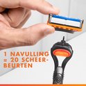 Hand houdt een Gillette scheermesje vast boven een scheermes handvat. 1 navulling = 20 scheerbeurten.