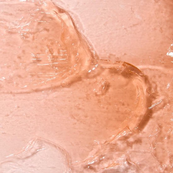 Textuur van perzikkleurige pomade met zichtbare golven en bubbels.