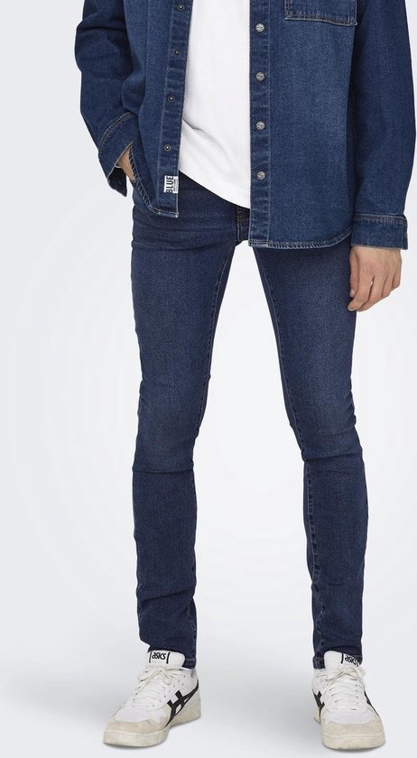 Model in een donkerblauwe skinny jeans, spijkerblouse en witte t-shirt, gezien vanaf de voorkant.