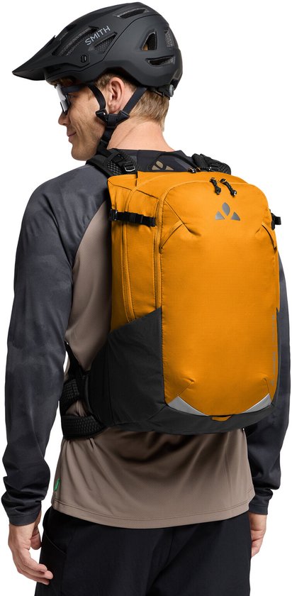 Man met helm en bril, draagt een oranje rugzak.