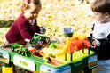 Een jongen en meisje spelen met een John Deere boerderij speeltafel met groene en gele speelgoedvoertuigen.