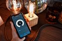 Een hand houdt een smartphone met Calex app, naast een gloeiende Calex lamp.
