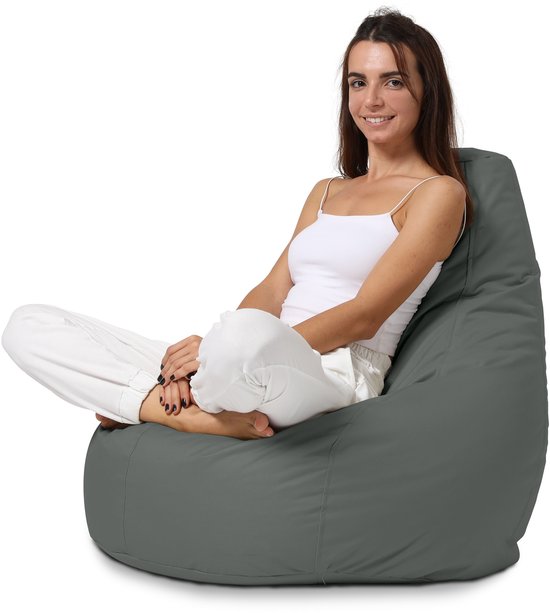 Vrouw in wit topje en witte broek zit op antracietkleurige zitzak.