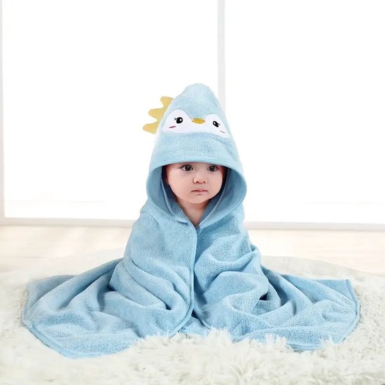 Bébé dans une cape de bain pingouin bleue à capuche sur fond blanc.