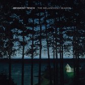 Albumhoes 'Benmont Tench - The Melancholy Season' met donkere bomen en een huisje aan een meer.