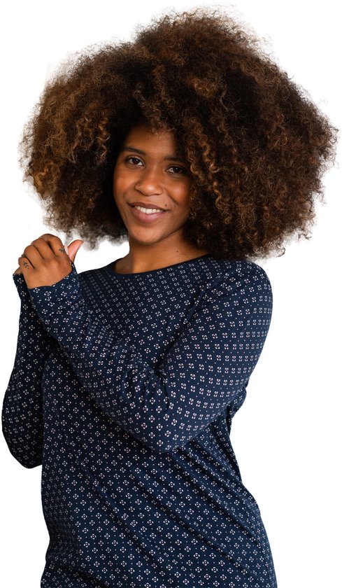 Close-up van een vrouw met een nachthemd met lange mouwen, donkerblauw met een all-over patroon van kleine witte vierkantjes.