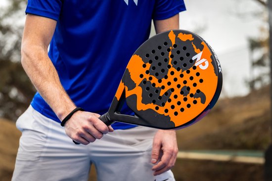 Persoon die een padelracket vasthoudt, met oranje en zwart camouflagepatroon, zwart handvat.