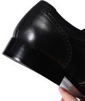 Hak van een zwarte leren veterschoen met suède details.