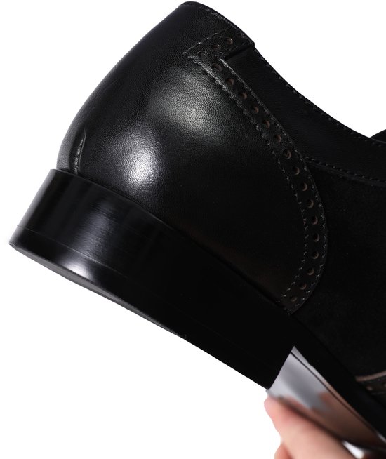 Hak van een zwarte leren veterschoen met suède details.