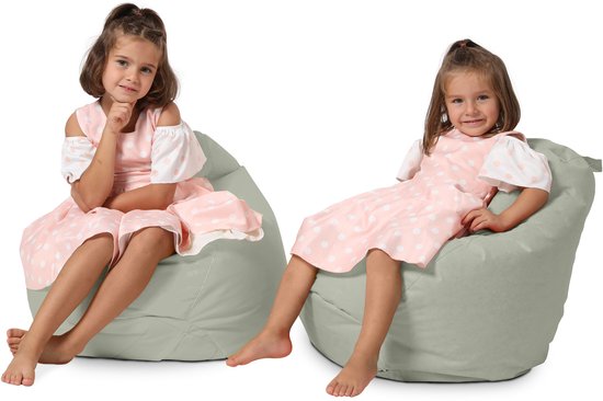 Twee meisjes in een roze jurk met witte stippen zitten op een grijze zitzak.