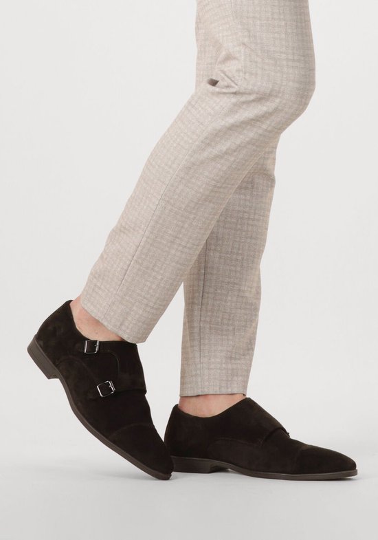 Heren benen in linnen broek en donkerbruine suède monk strap schoenen met dubbele gespen.