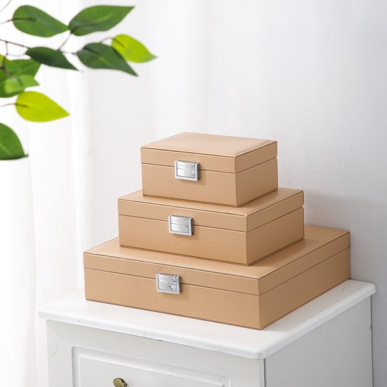 Drie beige opbergdozen van de Emilie Collection, gestapeld, met zilveren sluitingen.