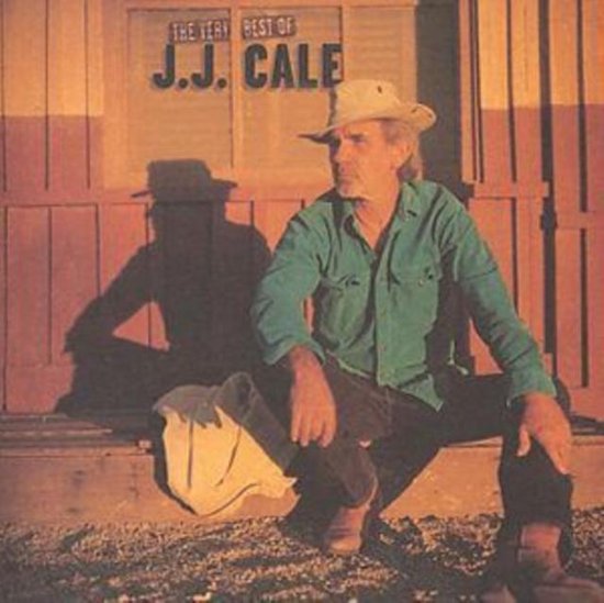 Man met hoed en groene blouse, zittend op een houten veranda. 'The Very Best Of' J.J. Cale.