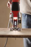Close-up van de voorkant van een oranje en zilveren Black+Decker decoupeerzaag die hout zaagt.