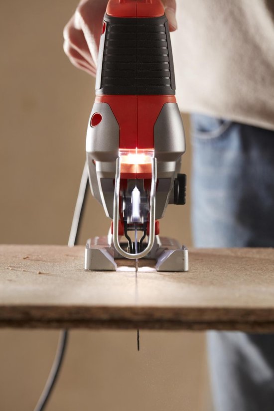 Close-up van de voorkant van een oranje en zilveren Black+Decker decoupeerzaag die hout zaagt.